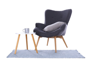 Photo of Comfortable armchair, rug and table isolated on white