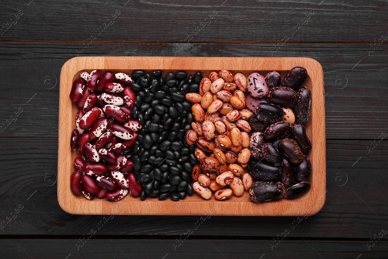 Plate with different kinds of dry kidney beans on wooden table, top view Photo of Plate with different kinds of dry kidney beans on wooden table, top view