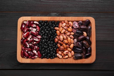 Photo of Plate with different kinds of dry kidney beans on wooden table, top view