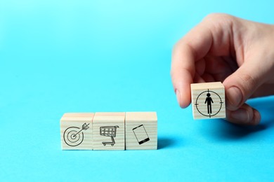 Image of Professional buyer. Woman putting wooden cube with human icon on light blue background, closeup