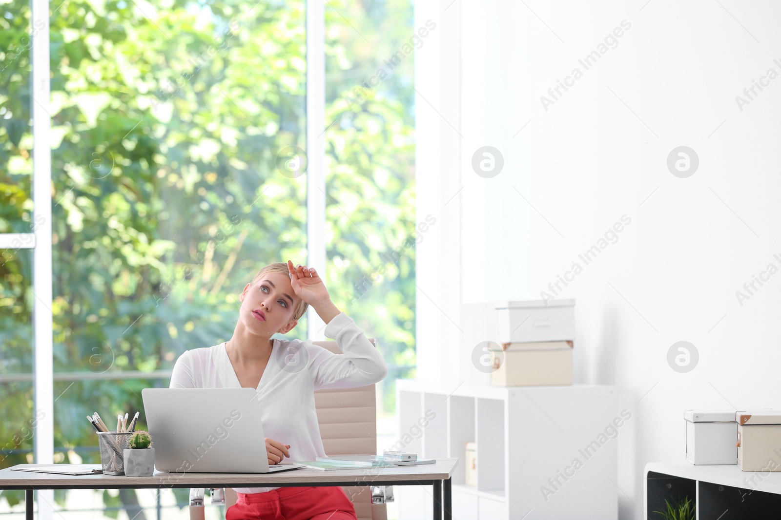 Photo of Young woman suffering from heat in office. Air conditioner malfunction