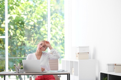 Photo of Young woman suffering from heat in office. Air conditioner malfunction