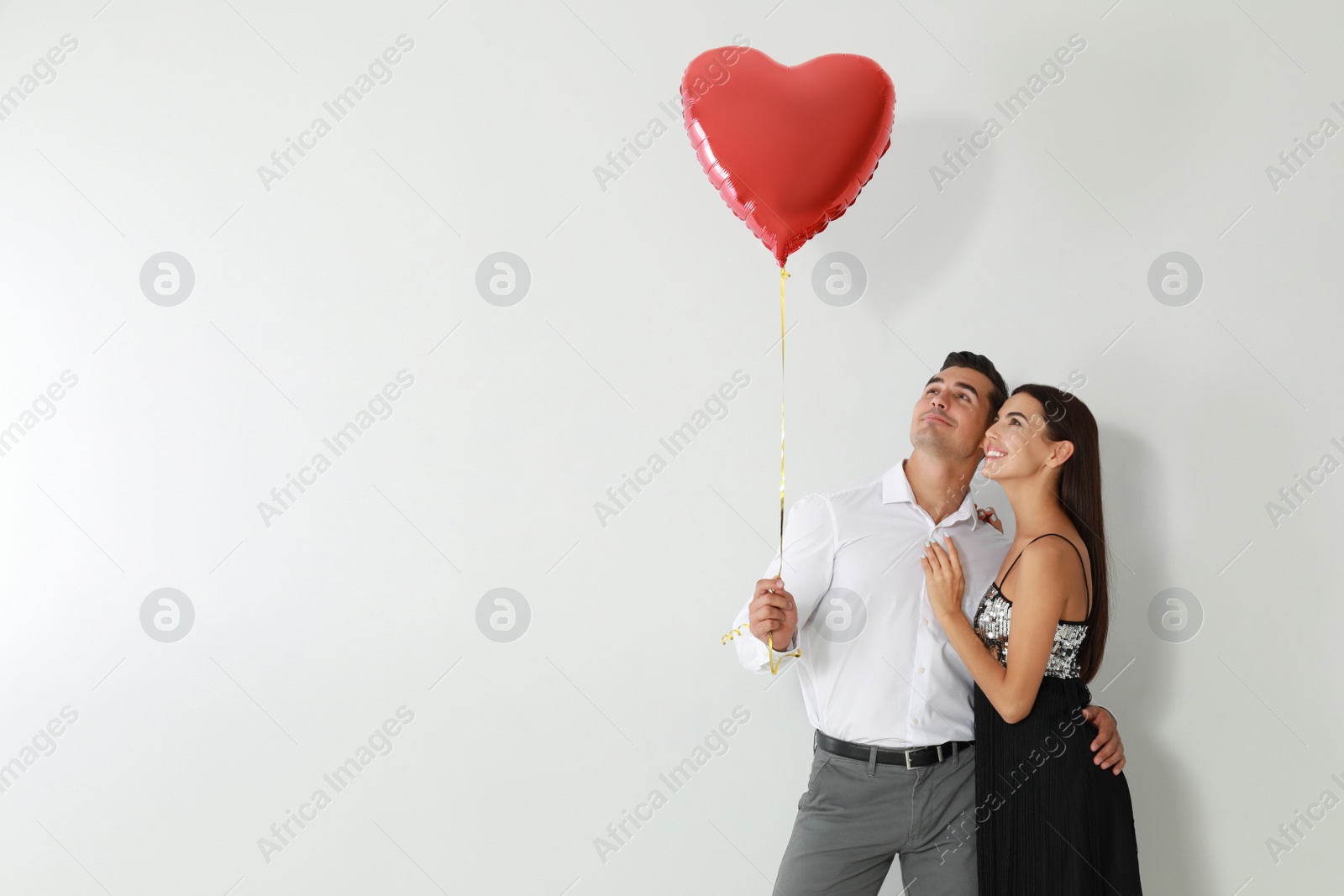 Photo of Beautiful couple with heart shaped balloon on light background, space for text