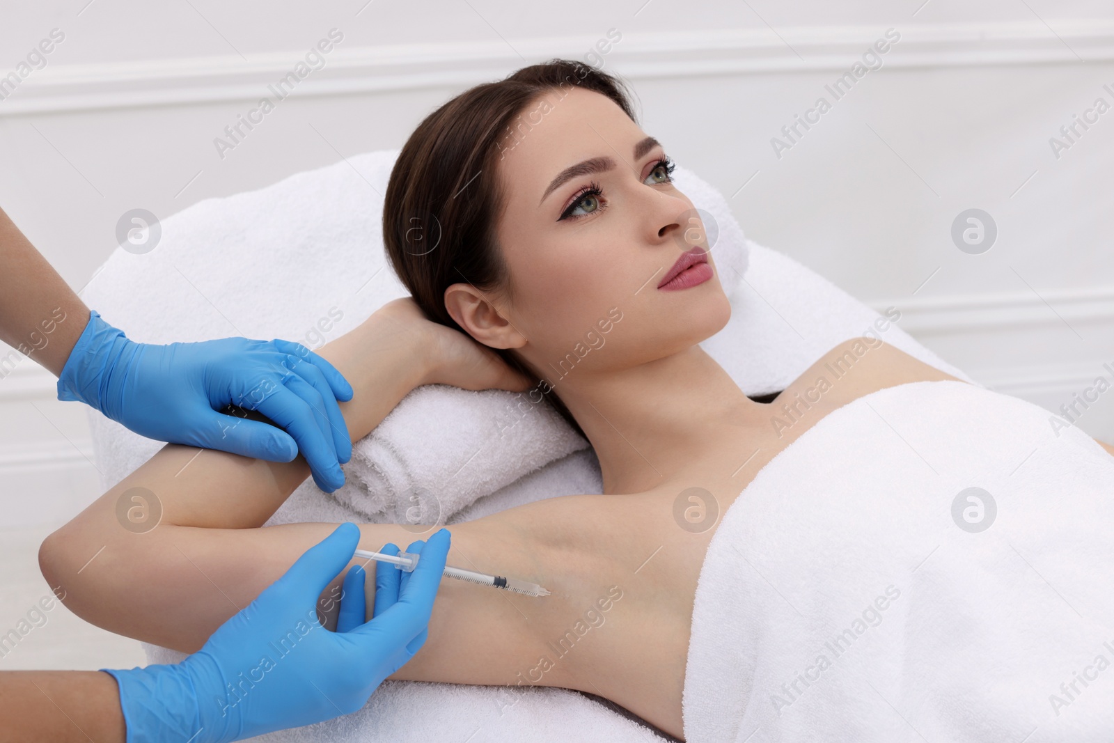 Photo of Cosmetologist injecting young woman's armpit in clinic. Treatment of hyperhidrosis