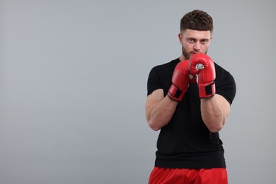 Photo of Man in boxing gloves on grey background. Space for text