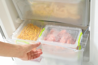 Photo of Woman opening refrigerator drawer with frozen products, closeup