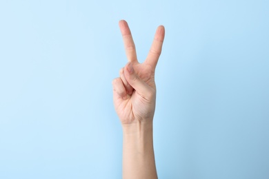 Photo of Woman showing number two on color background, closeup. Sign language
