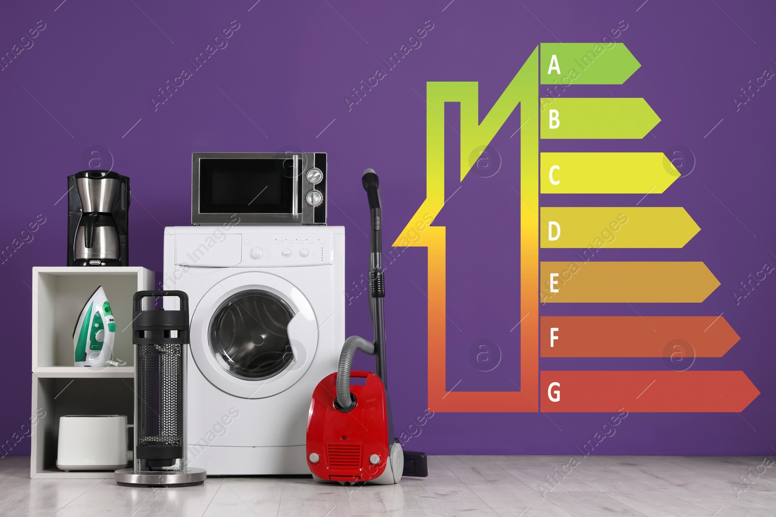 Image of Energy efficiency rating label and different household appliances near purple wall indoors