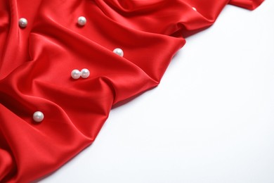 Photo of Texture of delicate red silk with pearls on white background
