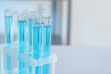 Photo of Test tubes with light blue liquid in laboratory, closeup. Space for text