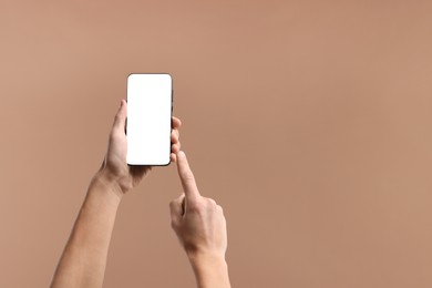Photo of Man using smartphone with blank screen on beige background, closeup. Mockup for design