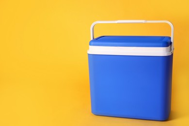 Photo of Closed blue plastic cool box on orange background. Space for text