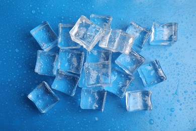 Photo of Ice cubes with water drops on light blue background, flat lay