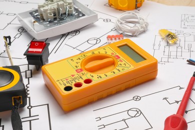 Photo of Wiring diagrams and different electrician's equipment on table, closeup