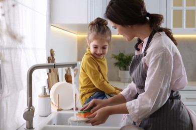 Young mother and her daughter spending time together in kitchen