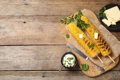 Photo of Tasty grilled corn on wooden table, flat lay. Space for text