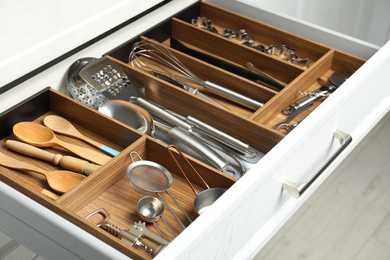Photo of Different utensils in open desk drawer indoors, closeup