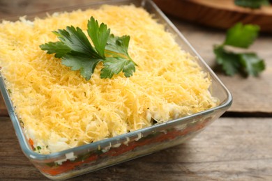 Photo of Traditional russian salad Mimosa served on wooden table, closeup