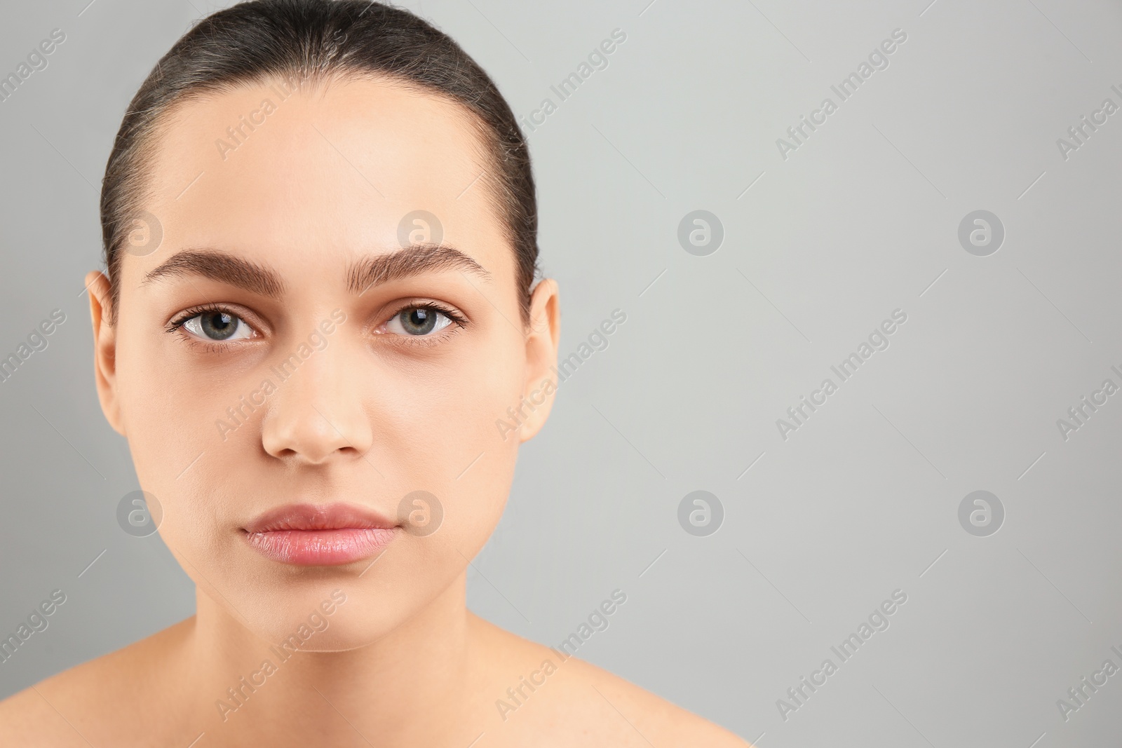 Photo of Young woman with perfect eyebrows on grey background, space for text