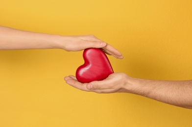 Photo of Man and woman holding decorative heart on color background, closeup