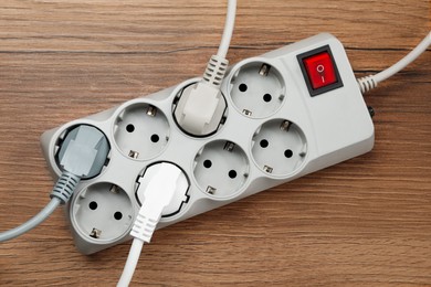 Photo of Power strip with extension cord on wooden floor, top view. Electrician's equipment