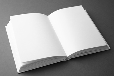 Photo of Open book with blank pages on dark grey background. Mock up for design