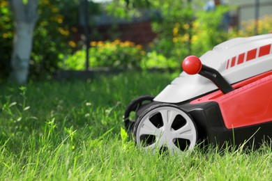 Photo of Lawn mower on green grass in garden, space for text