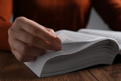 Photo of Woman reading Bible at wooden table, closeup