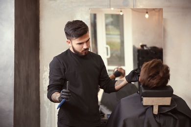 Professional hairdresser shaving client with straight razor in barbershop