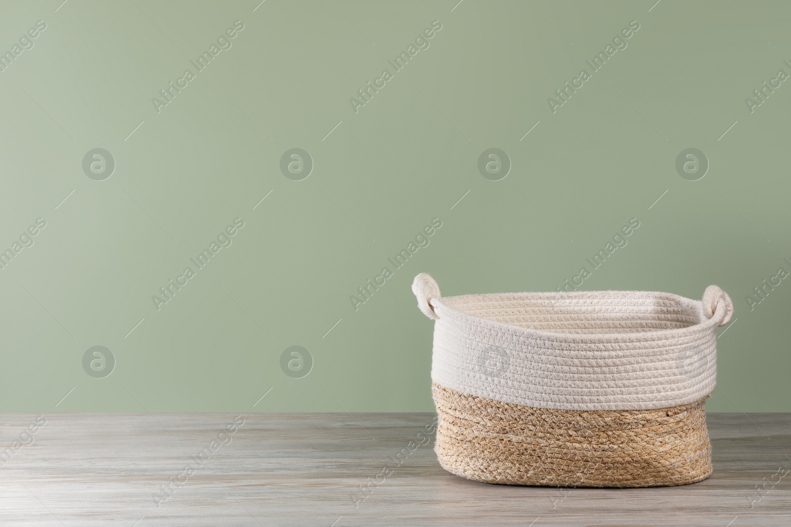 Photo of Empty wicker laundry basket near light green wall. Space for text