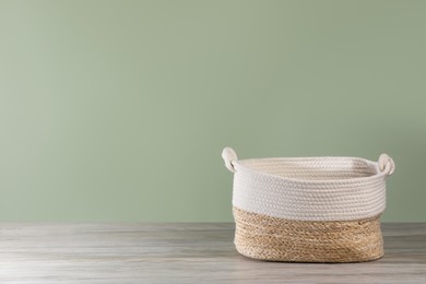 Photo of Empty wicker laundry basket near light green wall. Space for text