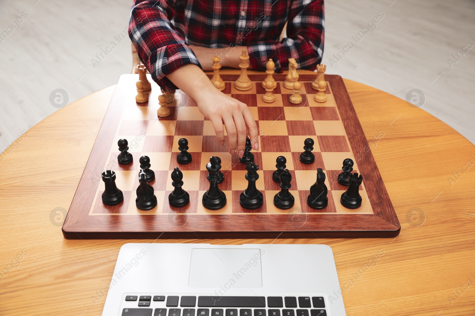 Photo of Woman playing chess with partner through online video chat at table indoors, closeup