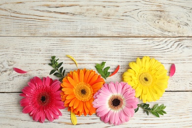 Photo of Flat lay composition with beautiful bright gerbera flowers on wooden background. Space for text