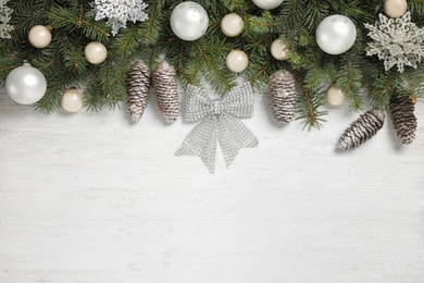 Photo of Fir branches with Christmas decoration on white wooden background, flat lay. Space for text