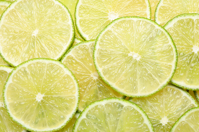 Photo of Many fresh juicy lime slices as background, top view