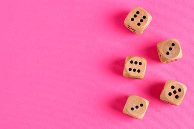 Photo of Many wooden game dices on pink background, flat lay. Space for text