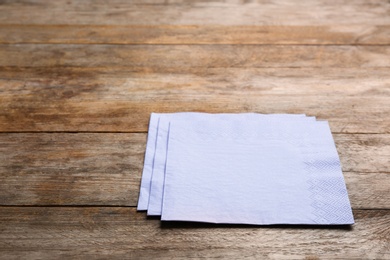Photo of Clean paper napkins and space for text on wooden background