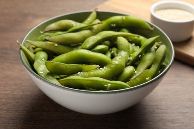 Photo of Bowl with green edamame beans in pods on wooden table