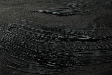 Photo of Beautiful strokes of black paint as background, closeup