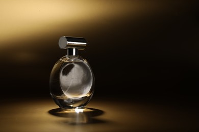 Luxury women's perfume. Sunlit glass bottle on golden background, space for text