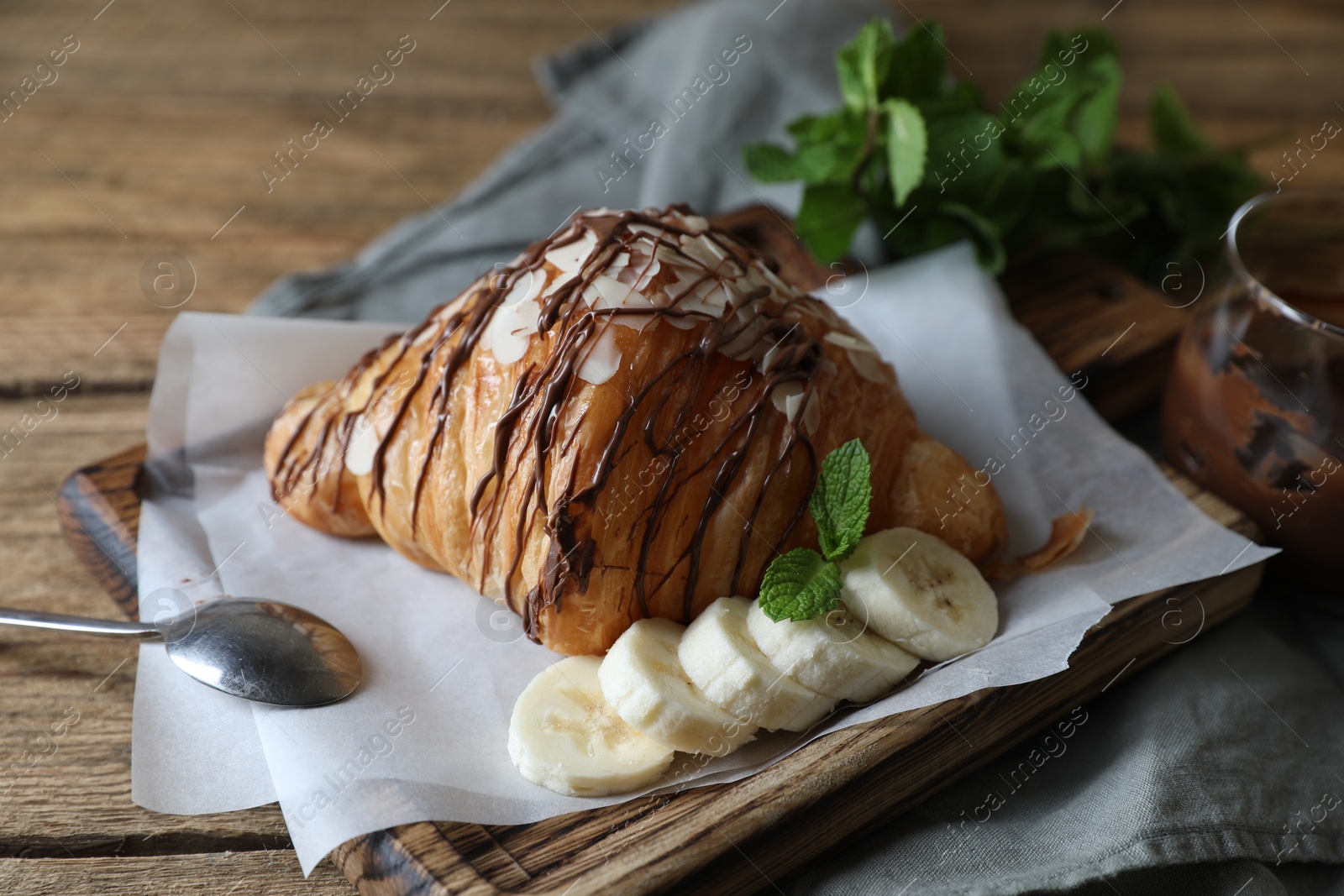 Delicious croissant with chocolate, banana and spoon on wooden table Photo of Delicious croissant with chocolate, banana and spoon on wooden table