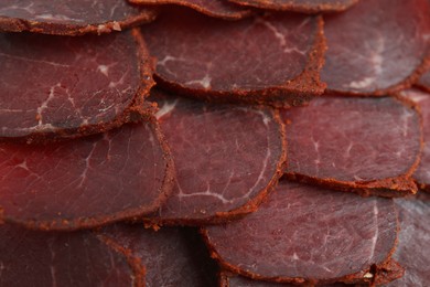 Photo of Delicious dry-cured beef basturma slices as background, top view
