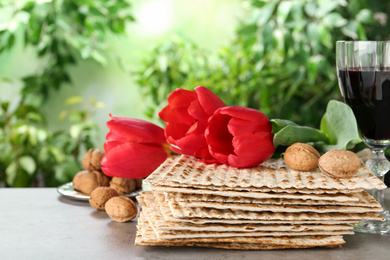 Photo of Traditional Matzos and tulips on grey table. Pesach (Passover) celebration