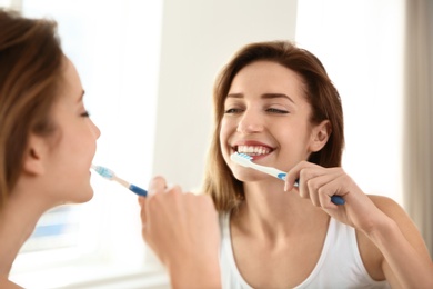 Young beautiful woman with toothbrush near mirror in bathroom. Personal hygiene