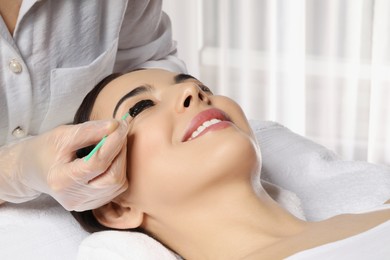 Photo of Young woman undergoing eyelash lamination and tinting in salon