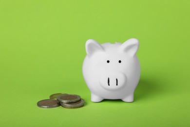 Photo of Ceramic piggy bank and coins on light green background. Financial savings