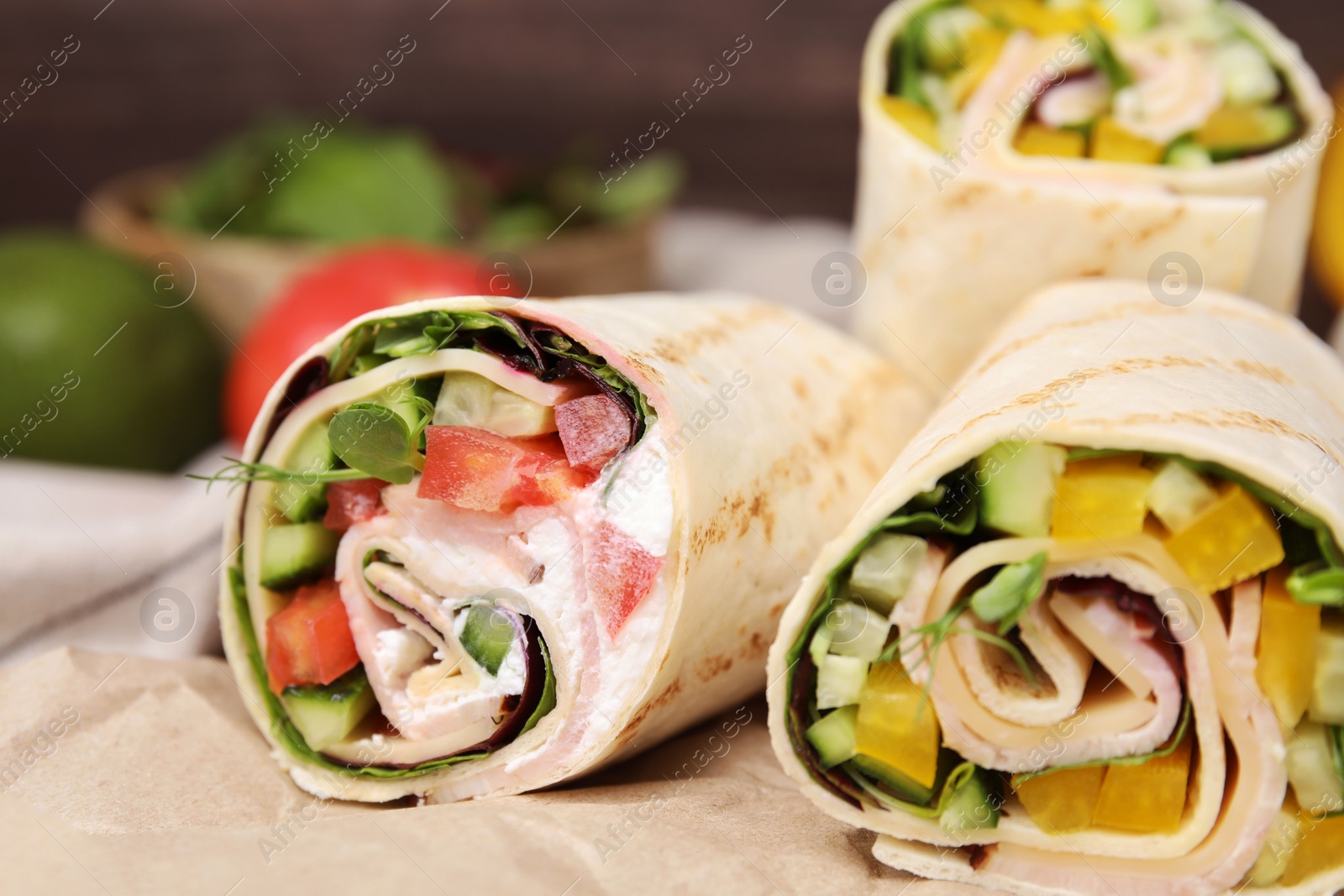Photo of Delicious sandwich wraps with fresh vegetables on parchment paper, closeup