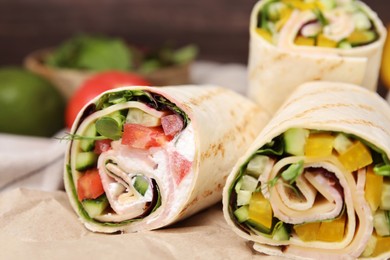 Photo of Delicious sandwich wraps with fresh vegetables on parchment paper, closeup