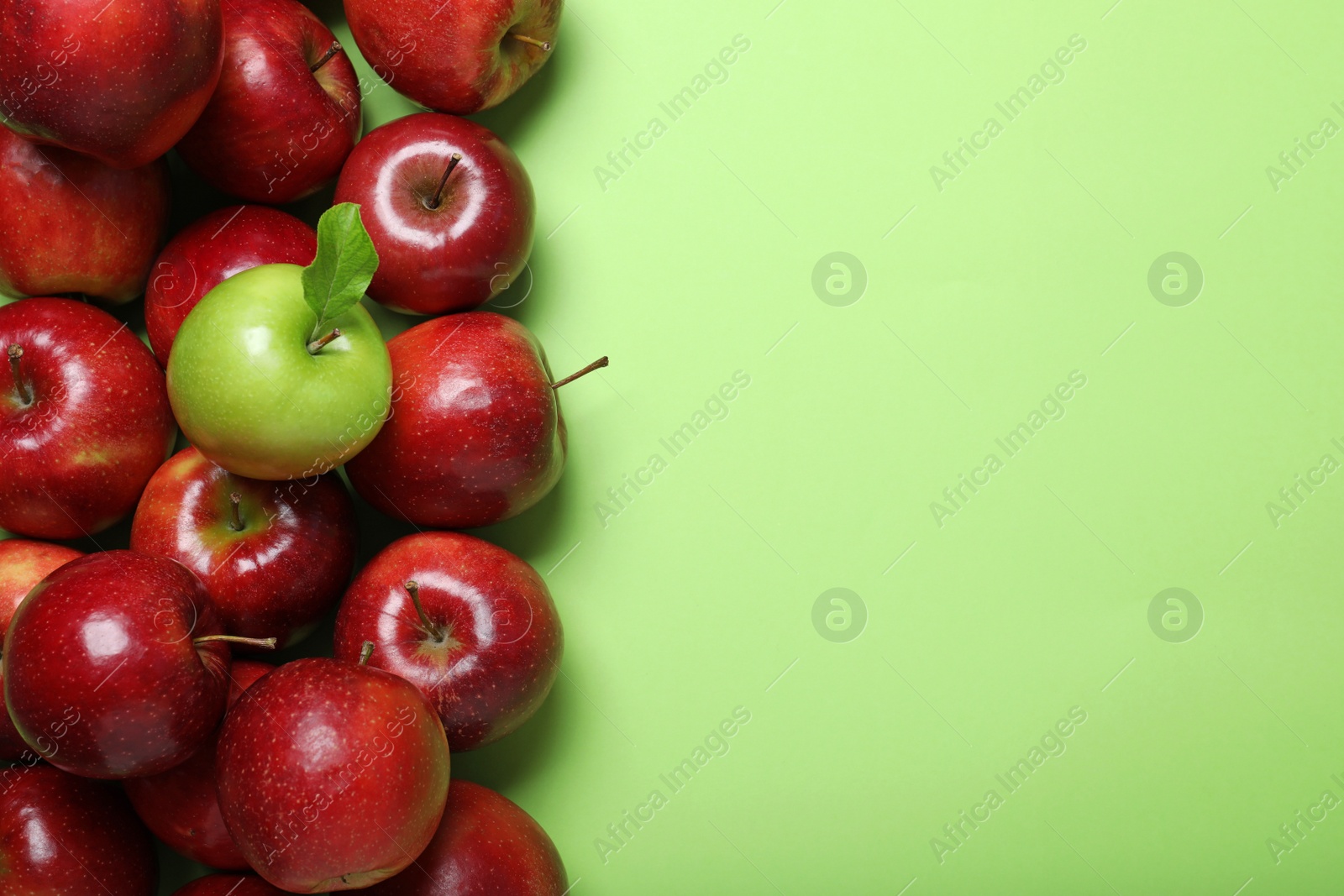 Photo of Tasty ripe apples on green background, flat lay. Space for text