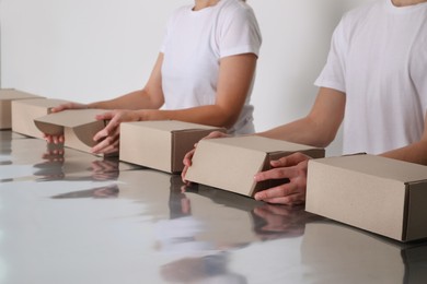 Photo of Workers folding cardboard boxes at table, closeup. Production line 